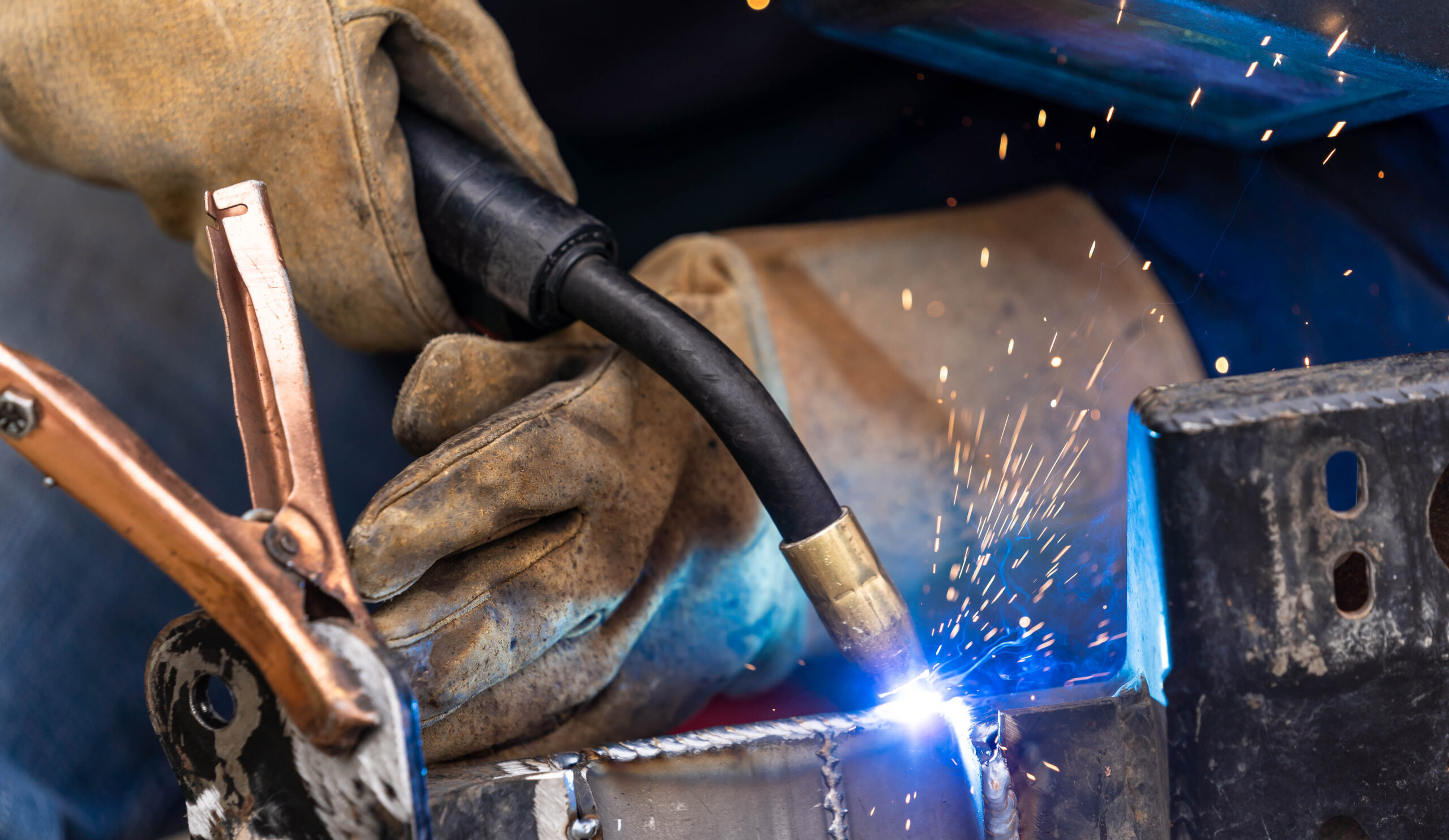 Gloved hands using a dual welder on metal