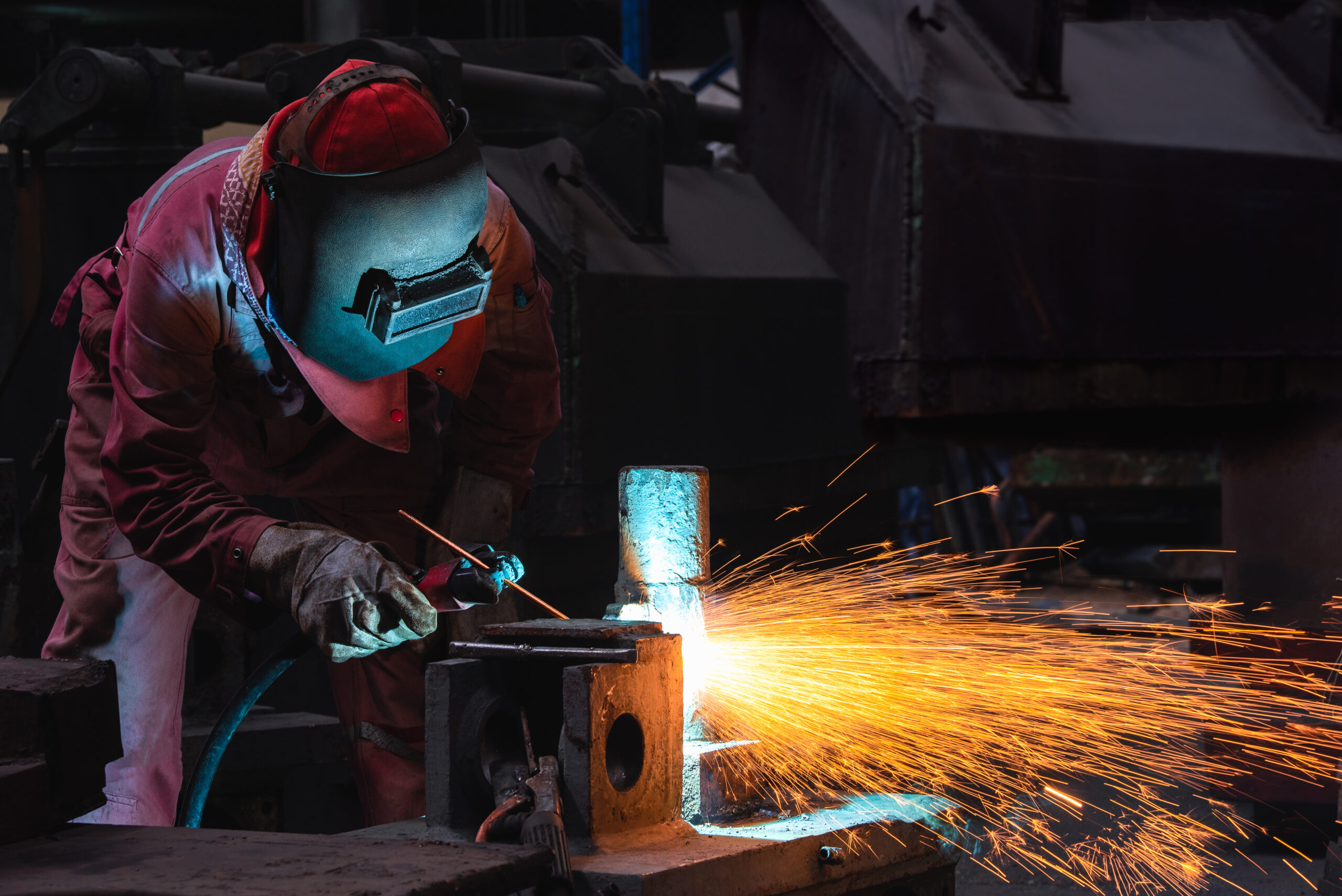 Welder air carbon arc gouging heavy steel structure in a factory.